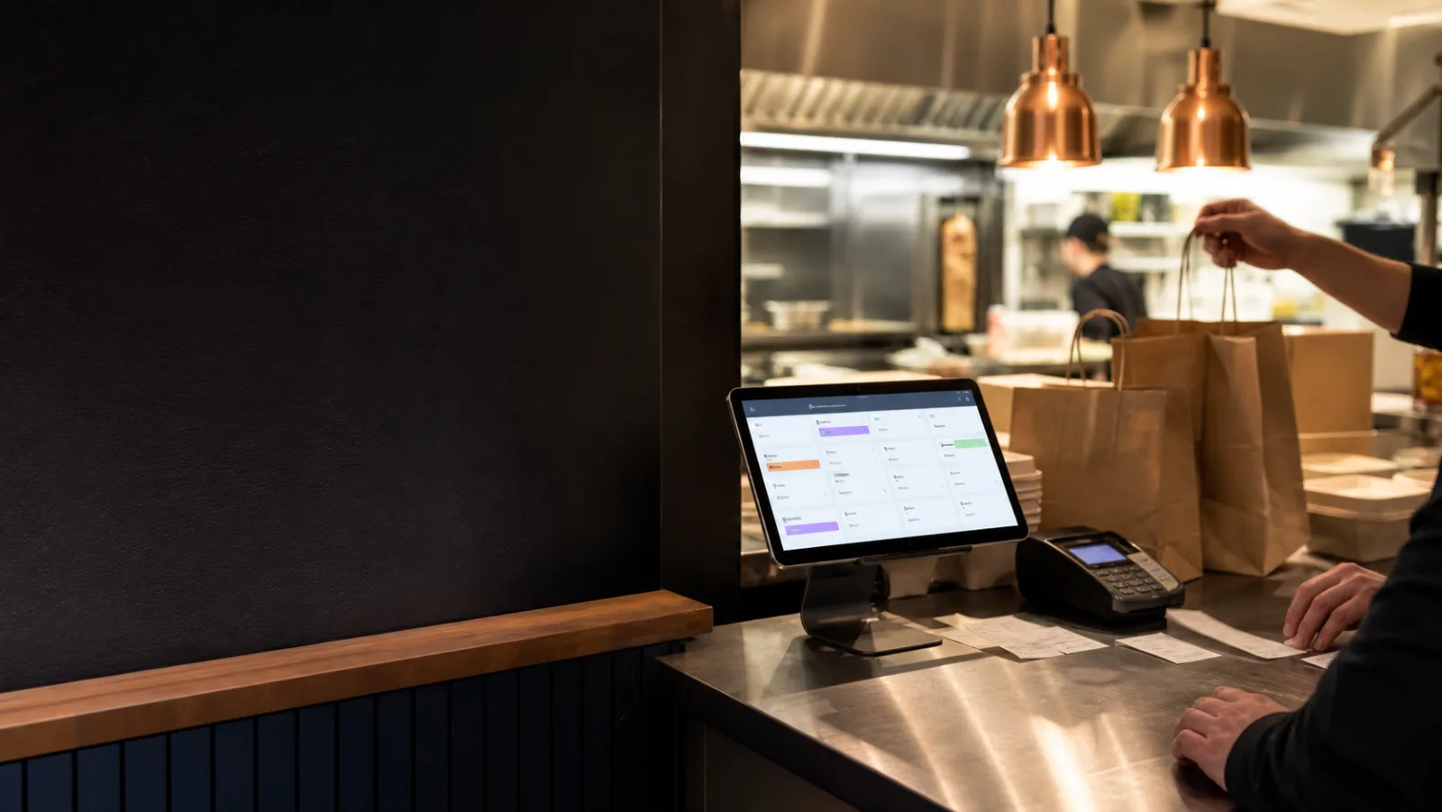 A takeaway counter with order bags, receipts and a staff tablet.